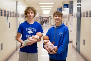 students hold newborn-looking dolls