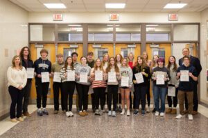 students hold certificates in high school hallway