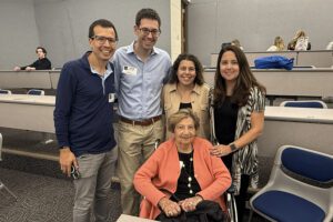 grown grandchildren stand around grandmother in wheelchair