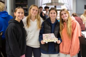 students hold a model food truck in a classroom kitchen