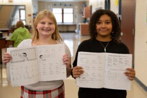 students hold up cursive workbooks