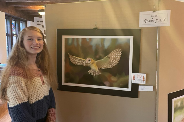 exeter's faith hartman poses by her artwork of an owl