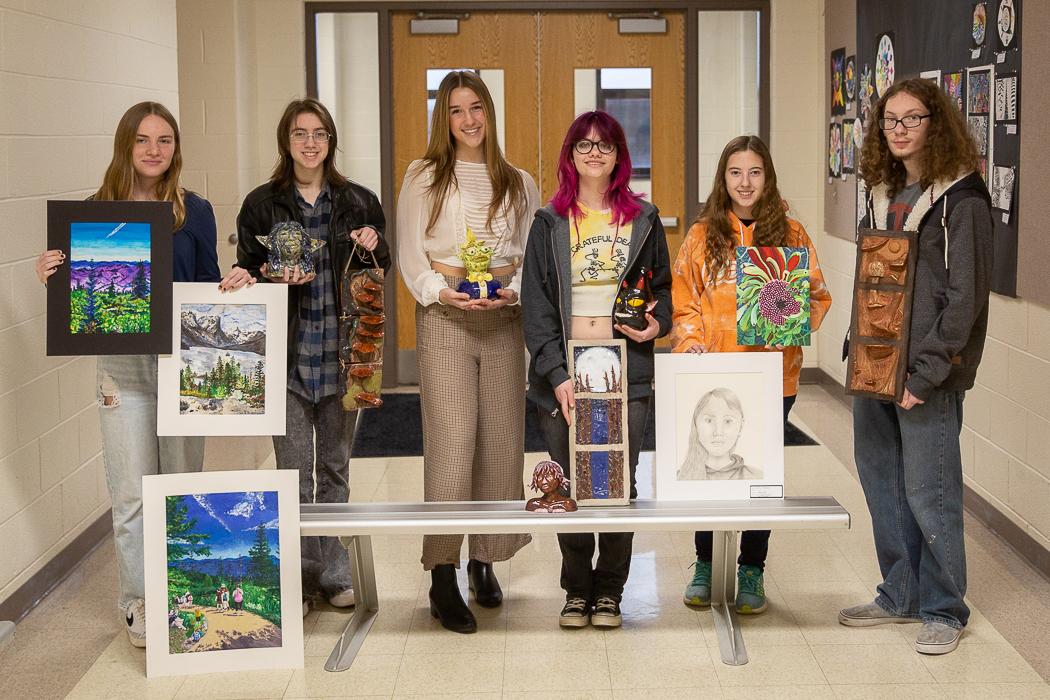students pose with their winning artwork