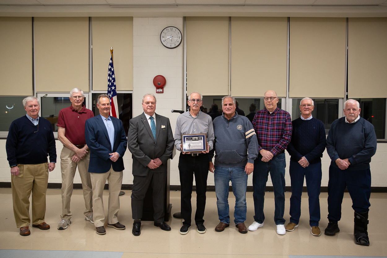 members of the 1971-72 basketball team stand and hold plaque