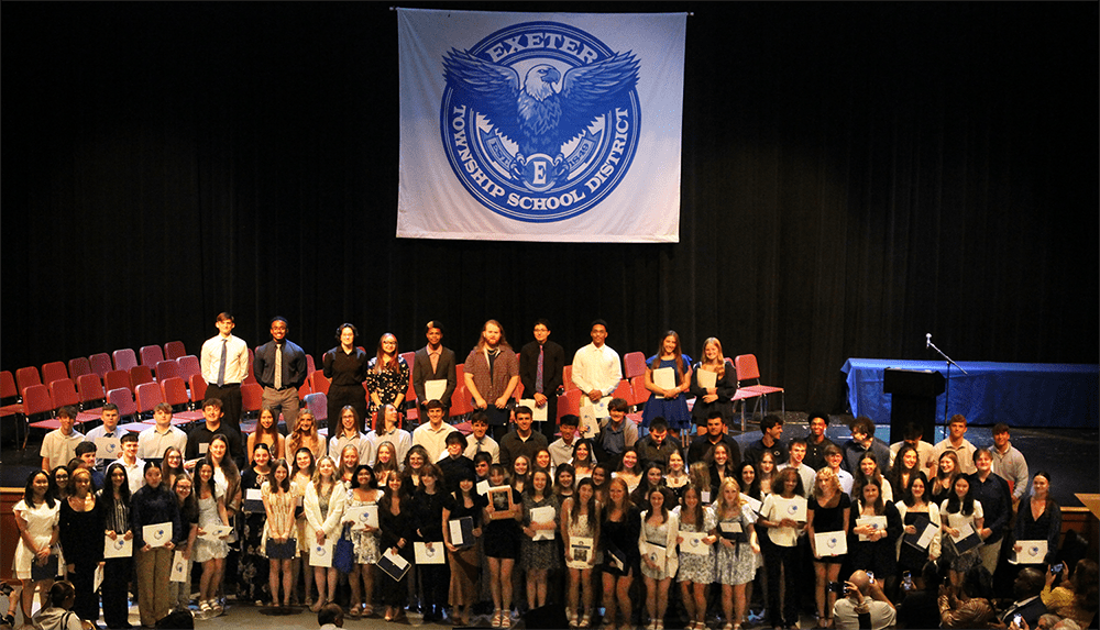 a large group of students hold awards on stage