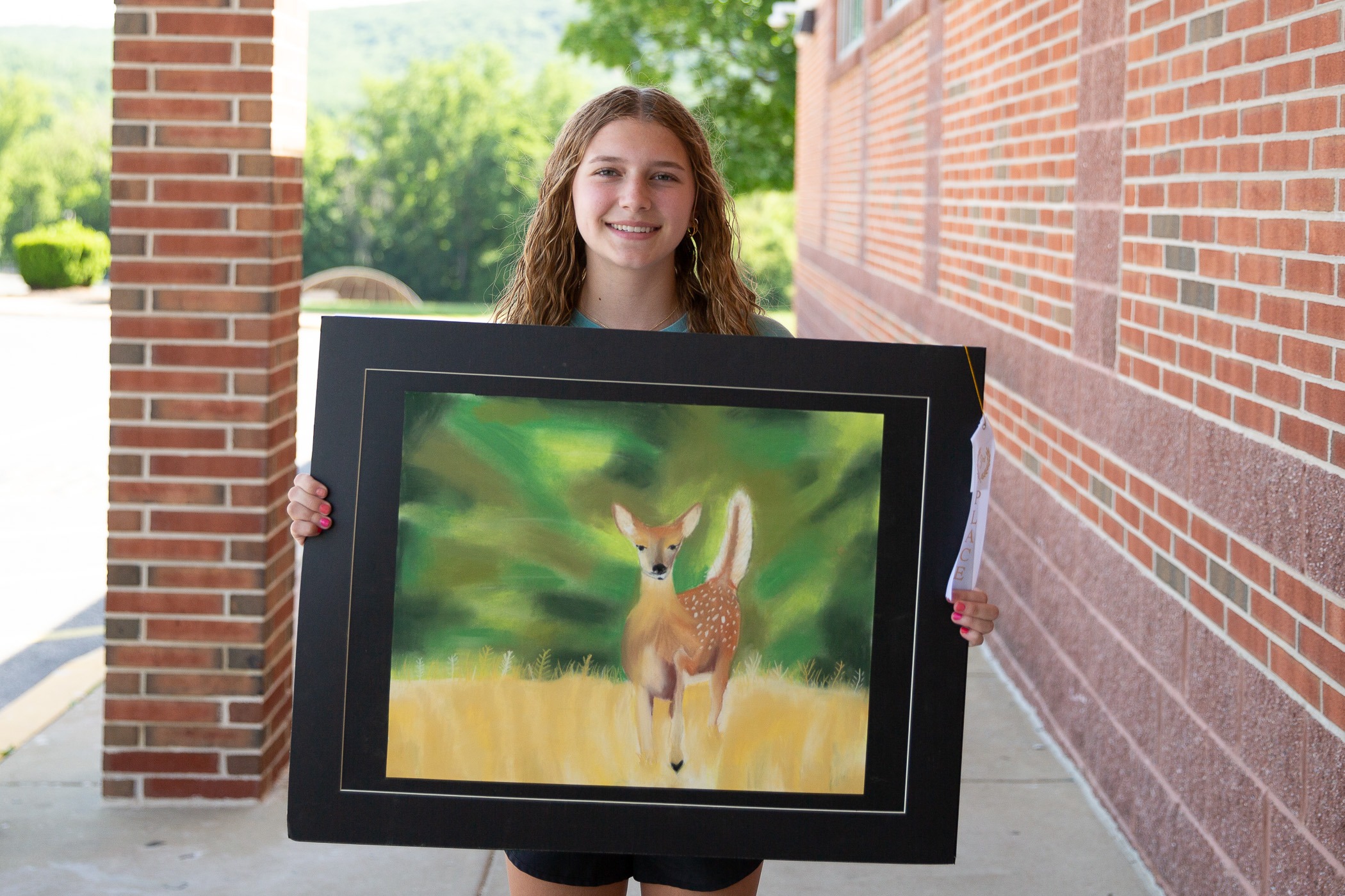 student shows off her pastel drawing of a deer
