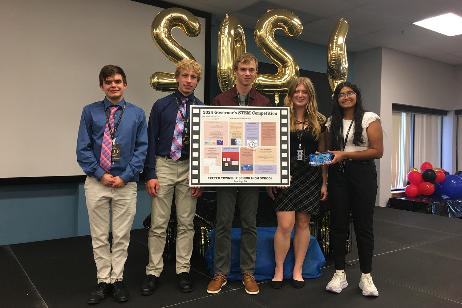 a small group of students hold their stem competition poster