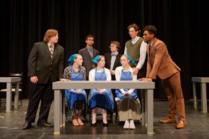 students stand around table in a theatrical pose