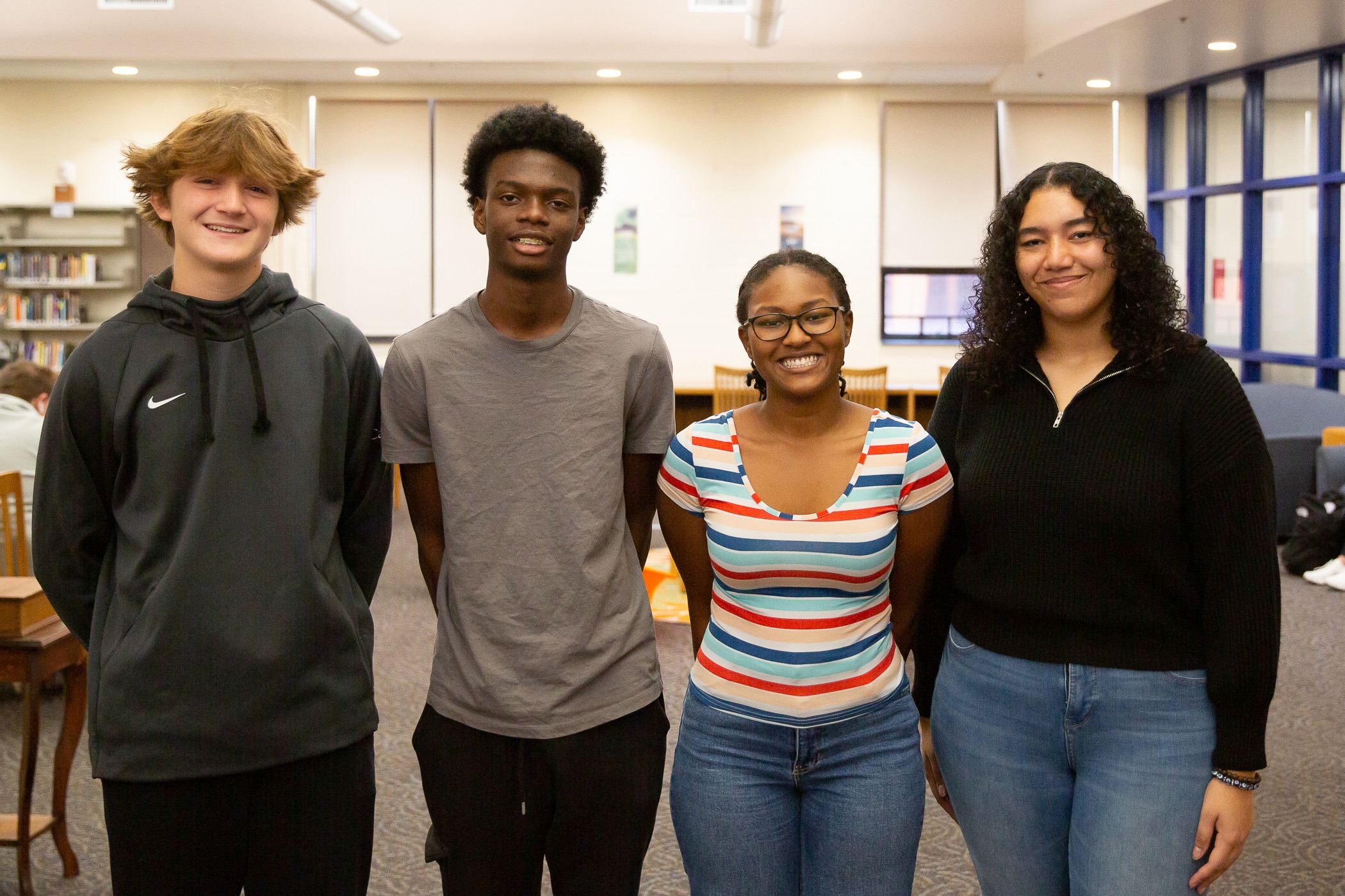 small group of students stand together in high school library