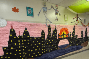 a colorful mural covers the wall of a high school depicting a city landscape