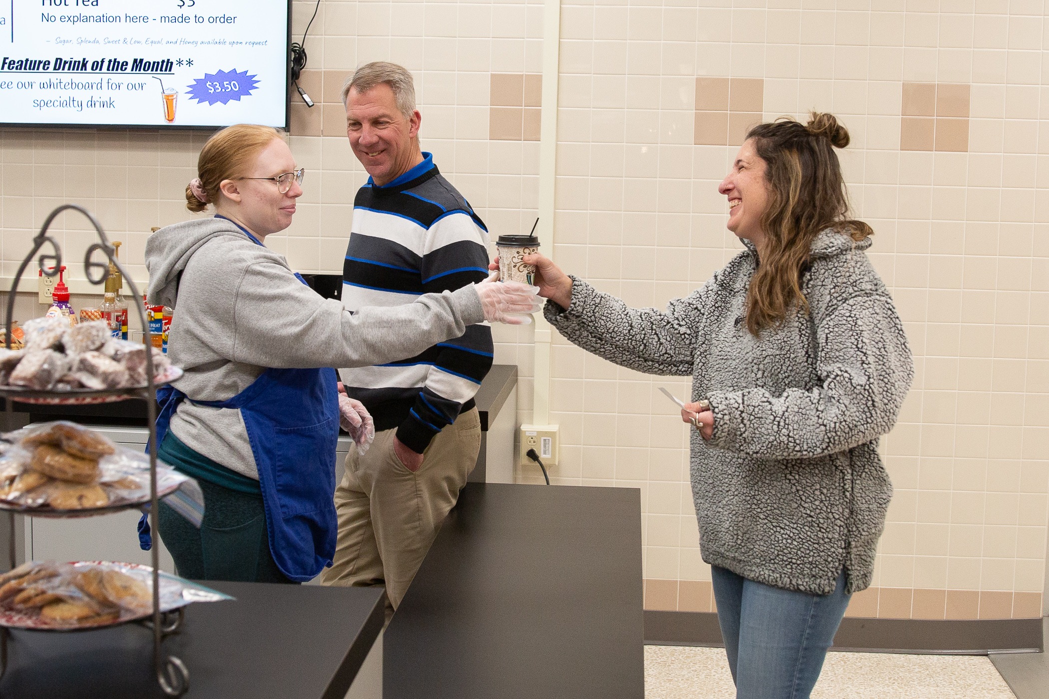 student hands a coffee to a staff member