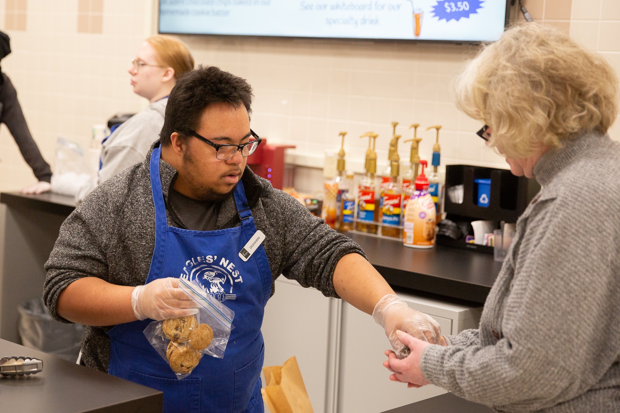 student hands a bag of cookies to a staff member