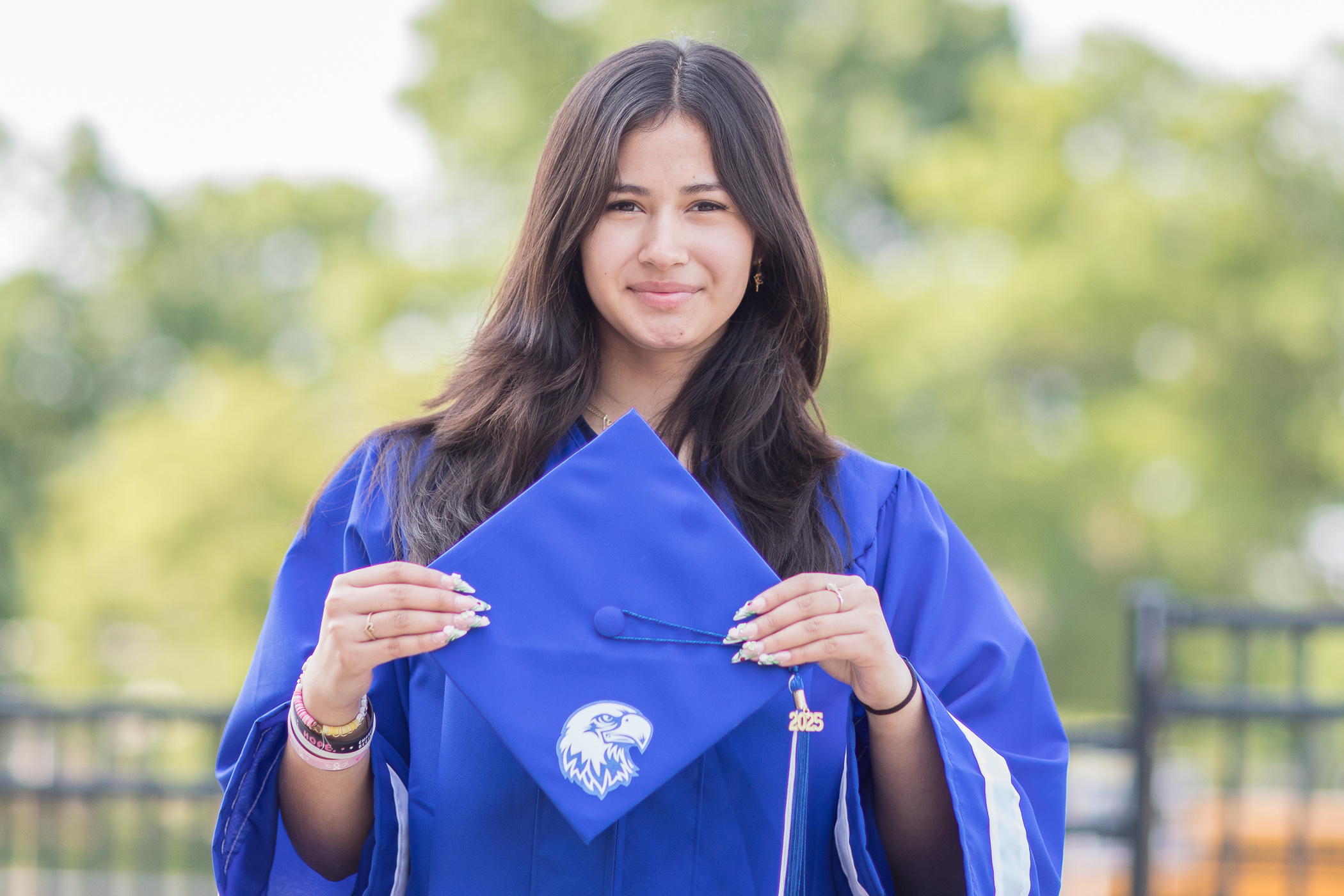 1R2A0720-2 student stands in graduate robe holding graduate hat